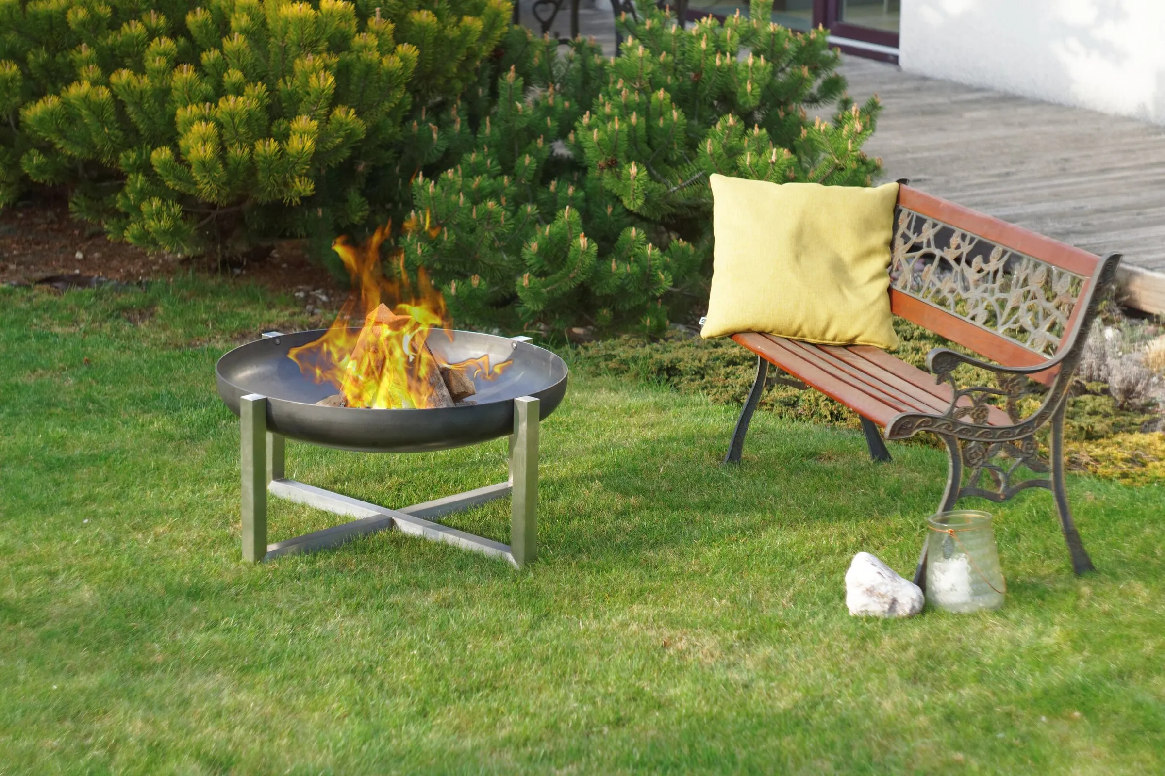 Feuerschale CROSS im Garten neben einer Gartenbank
