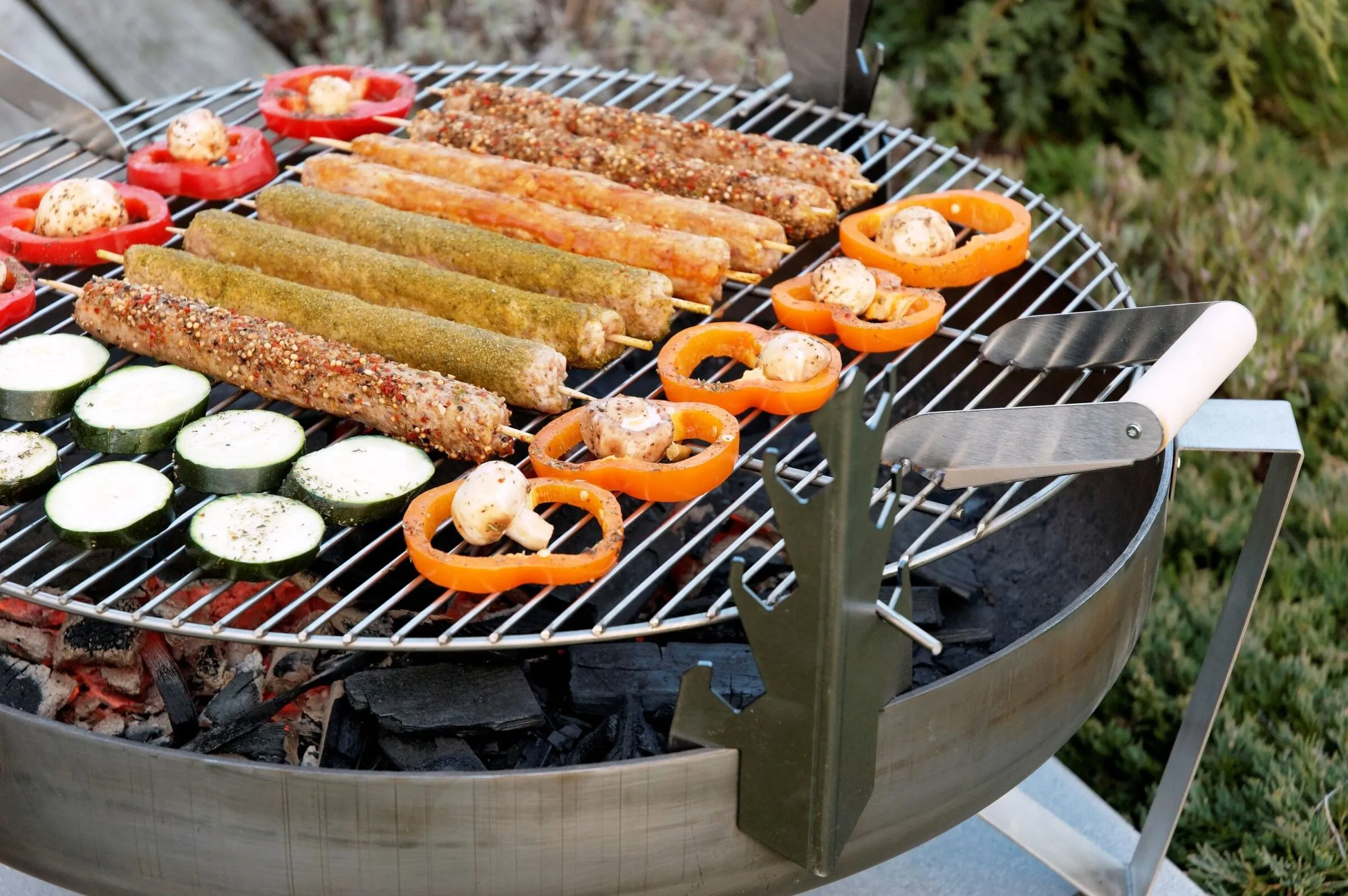 Grill-Aufsatz mit Würstchen und Gemüse über der Glut